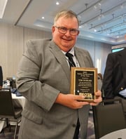 Tim Subler holding a plaque for his retirement.