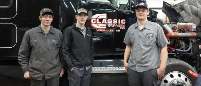 Young Classic Carriers mechanics infront of a black Classic Carriers truck.